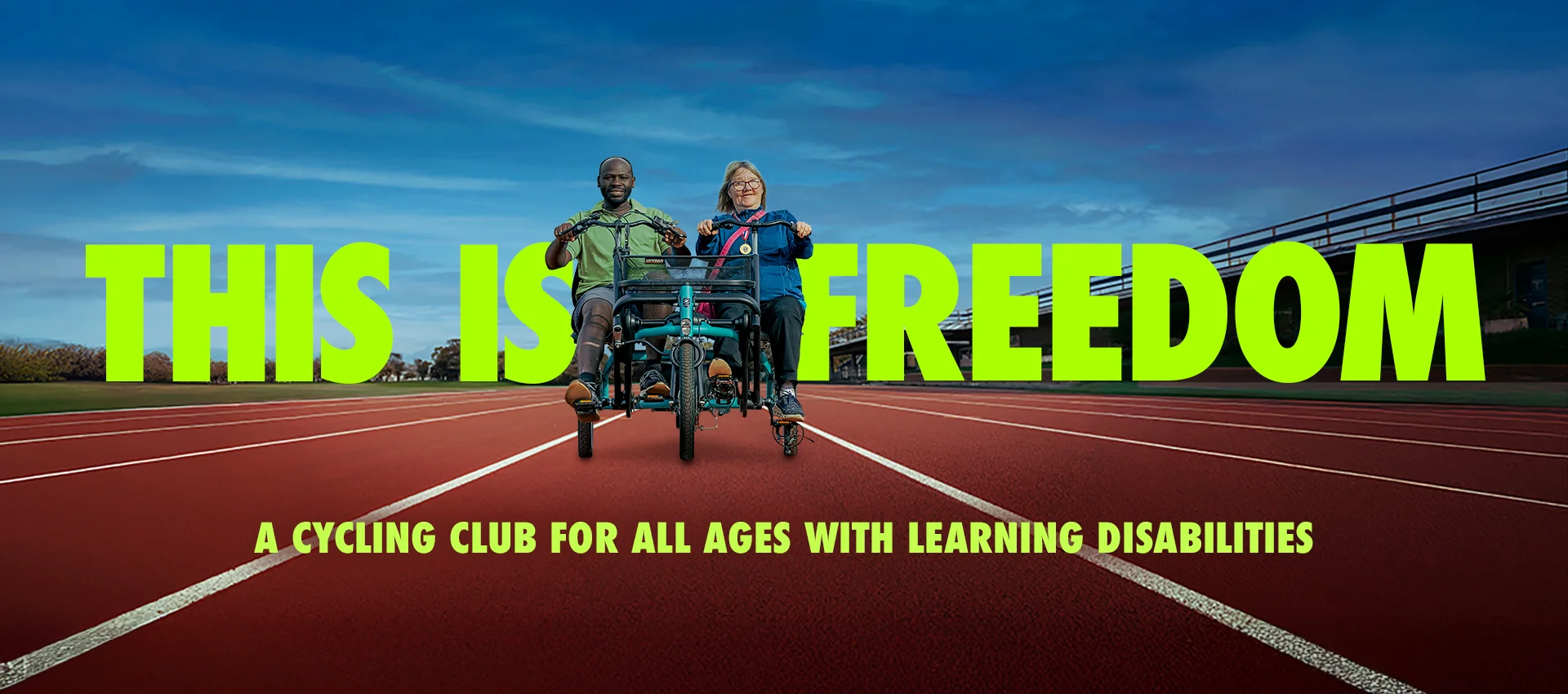 A photo of a woman and man riding side by side on a tricycle ona  running track, facing directly into the camera. Behind them in bold text is written 'This is freedom' and in the foreground 'a cycling club is for people of all ages with learning disabilities' 
